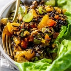 A serving dish with leafy greens and Fruit and Nut-Filled Wild Rice Salad