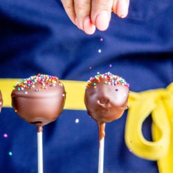 Sprinkles being sprinkled on top of chocolate cake pops.