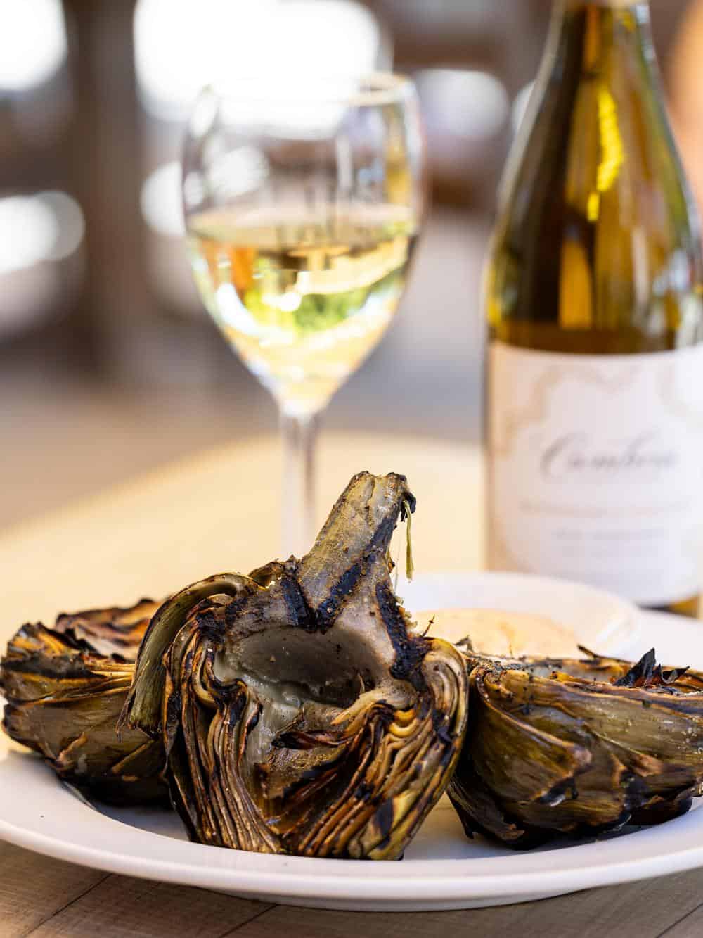 Grilled Castroville artichoke with mustard dipping sauce and a glass of white wine