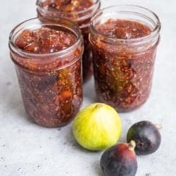 Jars of jam next to fresh figs.