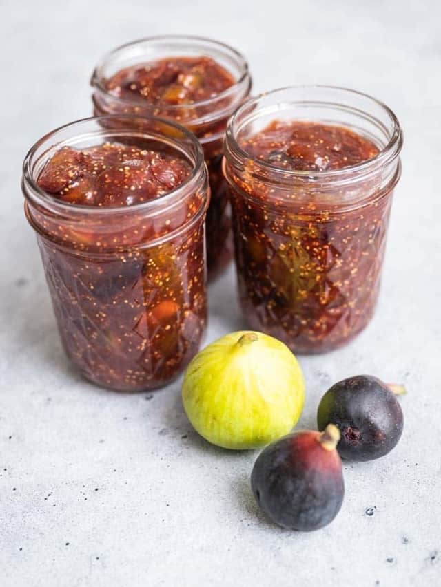 Jars of jam next to fresh figs.