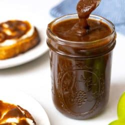 Apple butter in a jar being served on toast