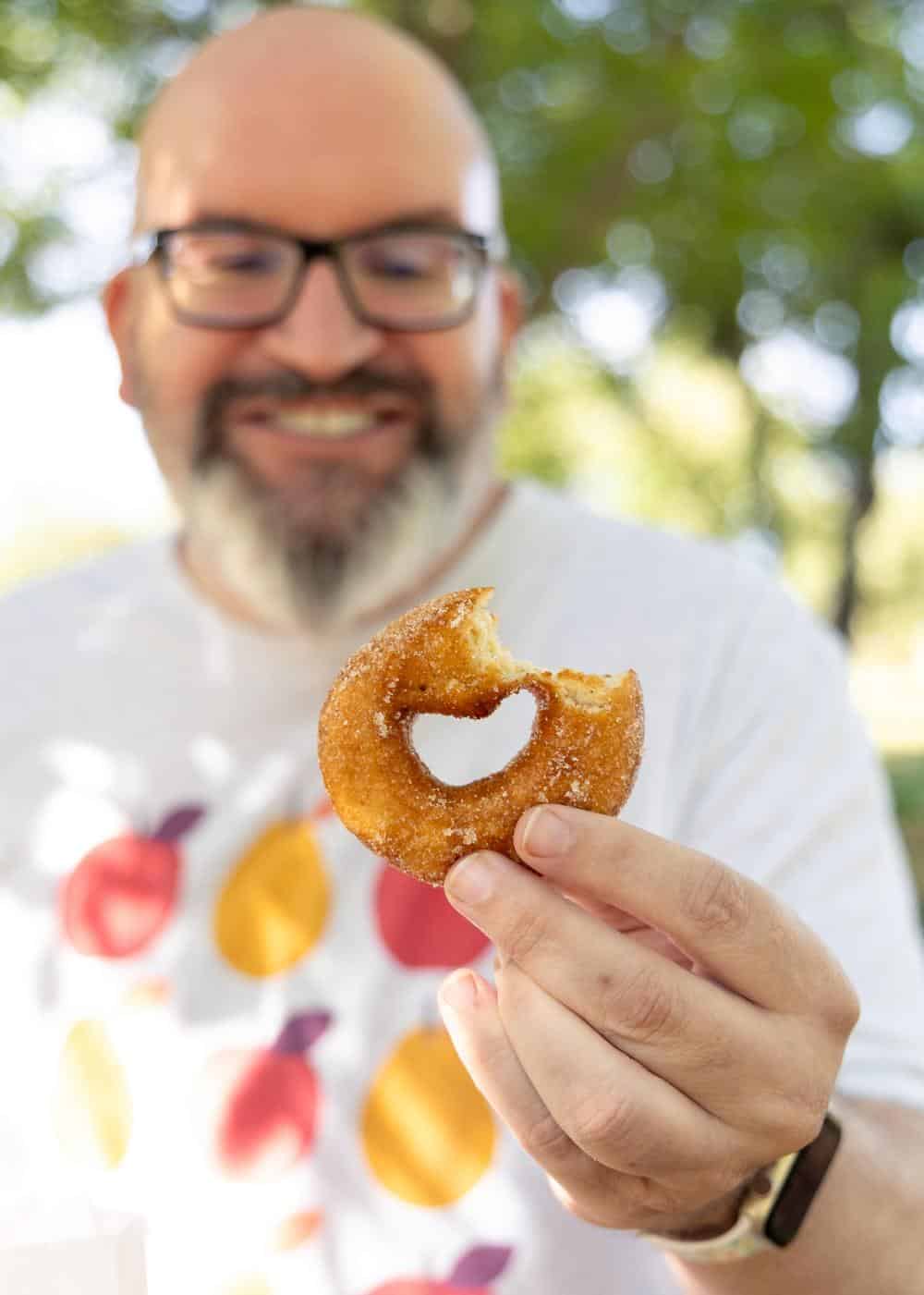 Jerry James Stone holding an apple cider donut from Rainbow Orchards