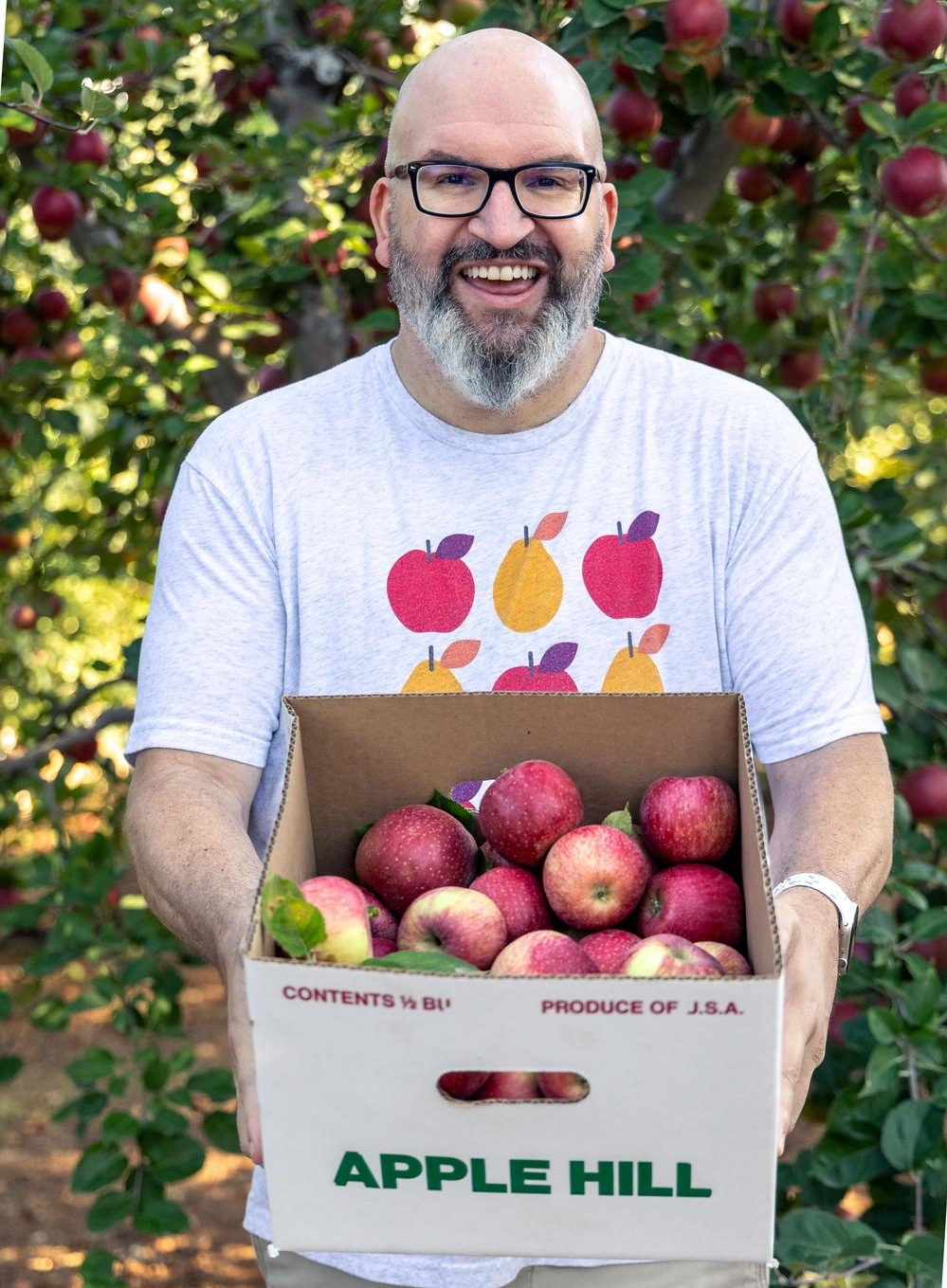 Jerry James Stone holding a box of apples at a u-pick apple farm