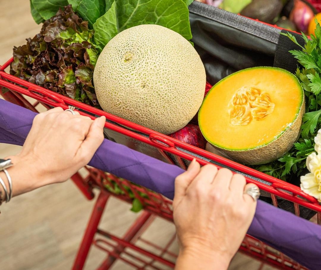 Shopping cart full of fruit and vegetables including Cantaloupes