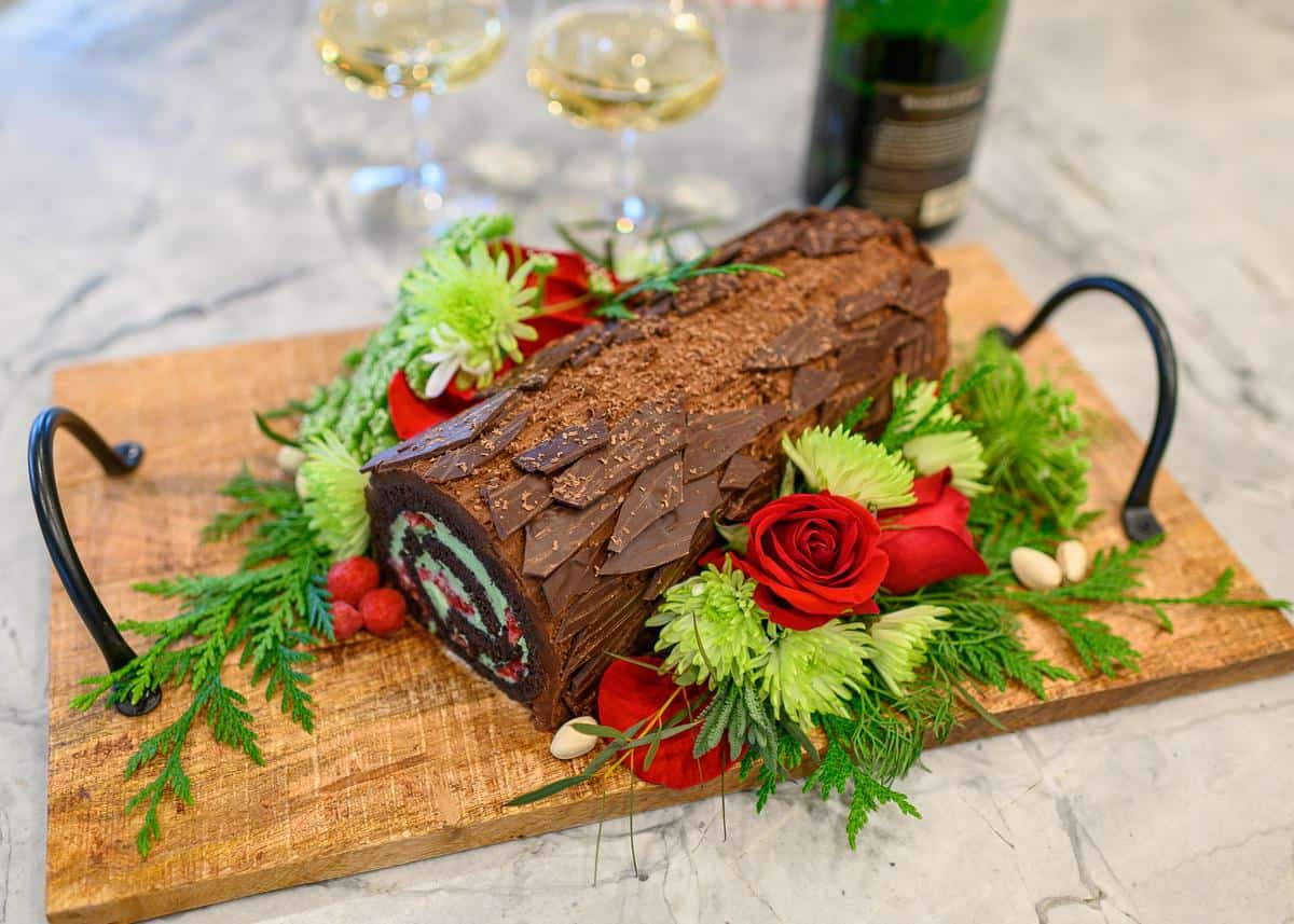 yule log on a board surrounded by flowers and holiday greenery