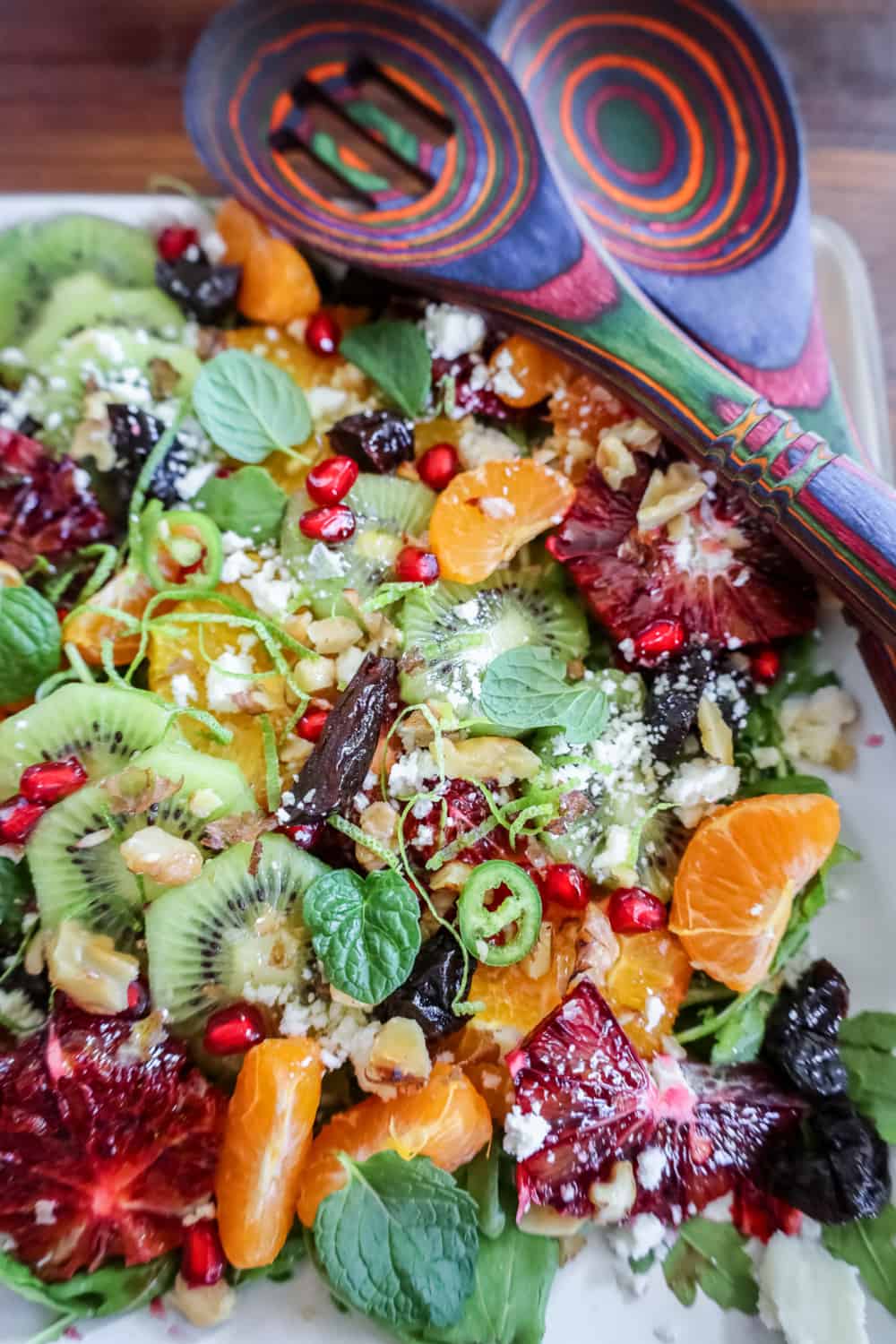 winter fruit salad on a platter with colorful salad utensils