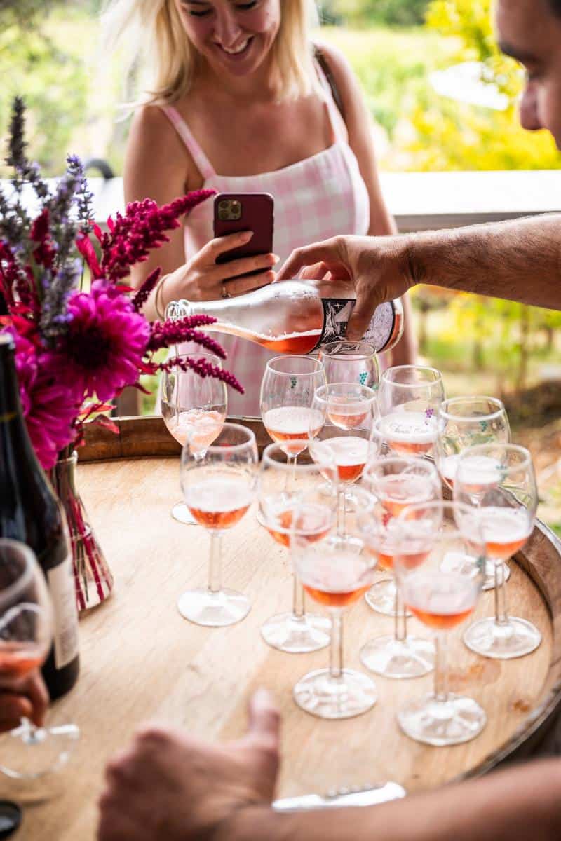 pouring rose into many wine glasses at a winery for a wine tasting