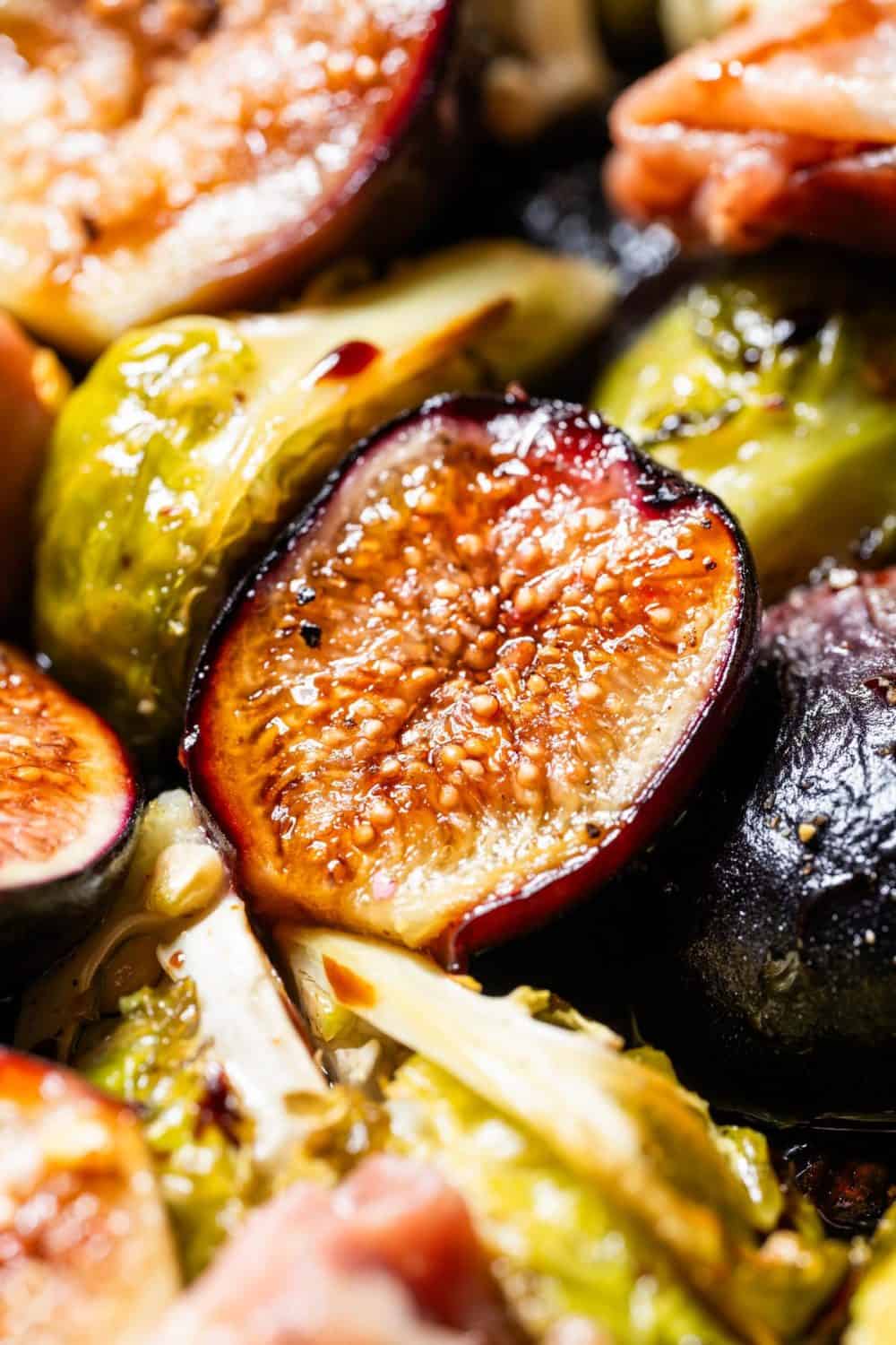 close up of a roasted fig on a sheet pan with brussels sprouts