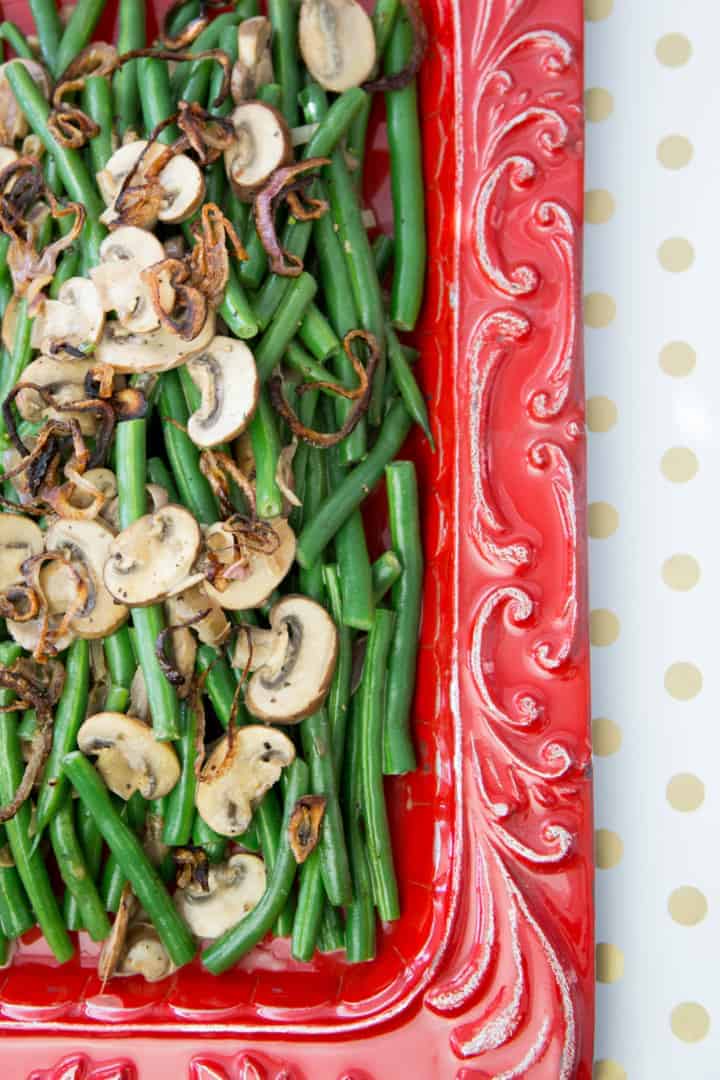 sauteed green beans with mushrooms on a red platter