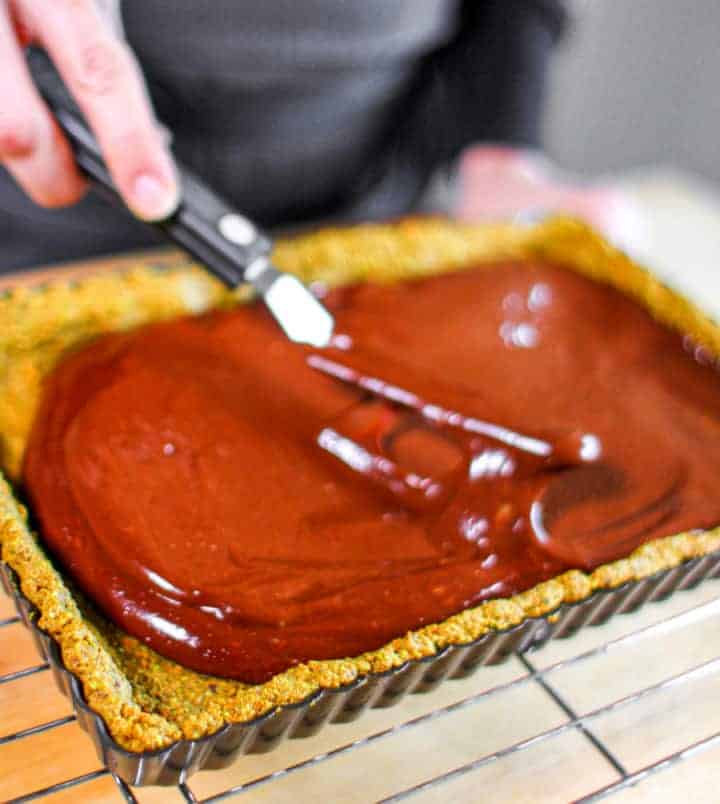 woman spreading chocolate filling into G-Free Foodie's Pistachio Tart Shell