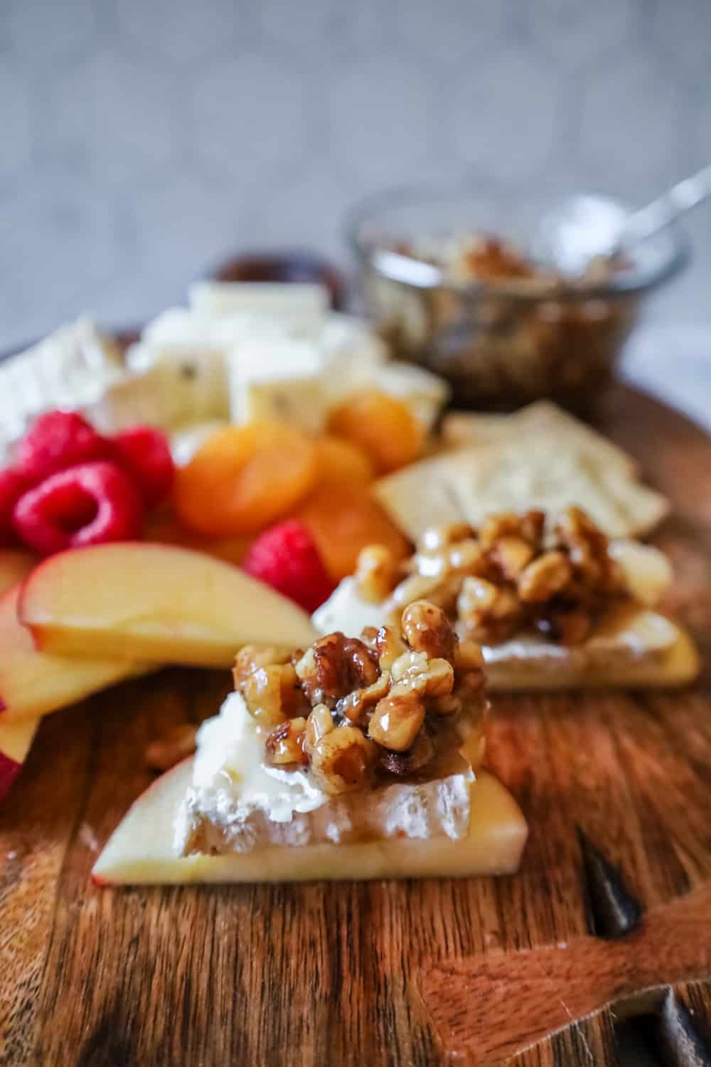 wet walnuts on apple slices topped with brie on a cheeseboard