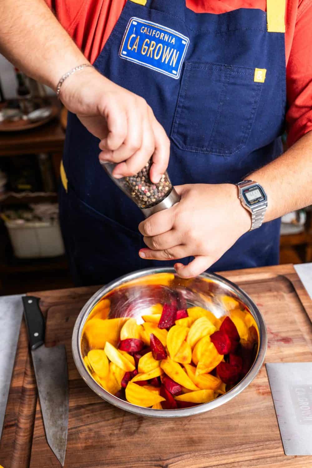 adding pepper to a bowl of roasted beets