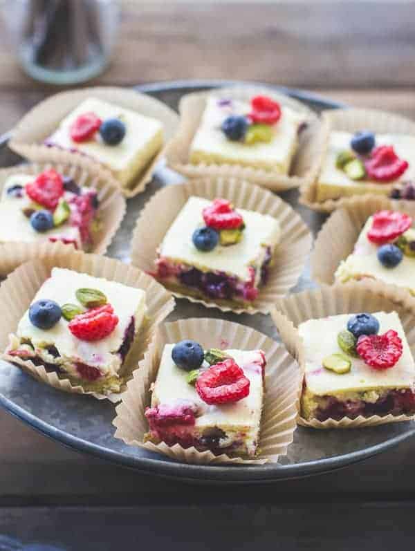 chevre cheesecake squares with pistachio crust topped with fresh berries