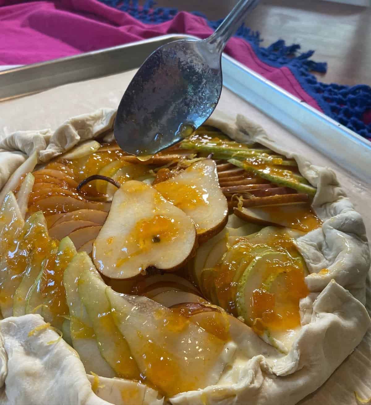 spooning apricot jam over sliced pears