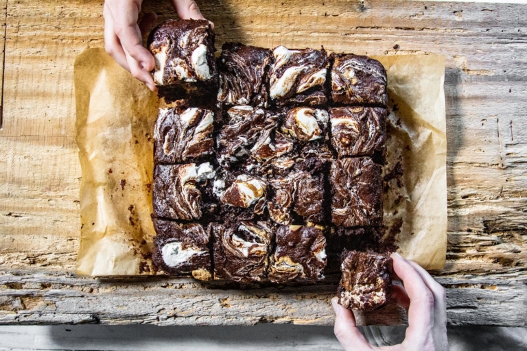 hands reaching for sweetpotato swirled brownie slices