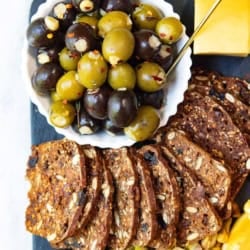 Stuffed olives and raisin crackers on a cheese board.
