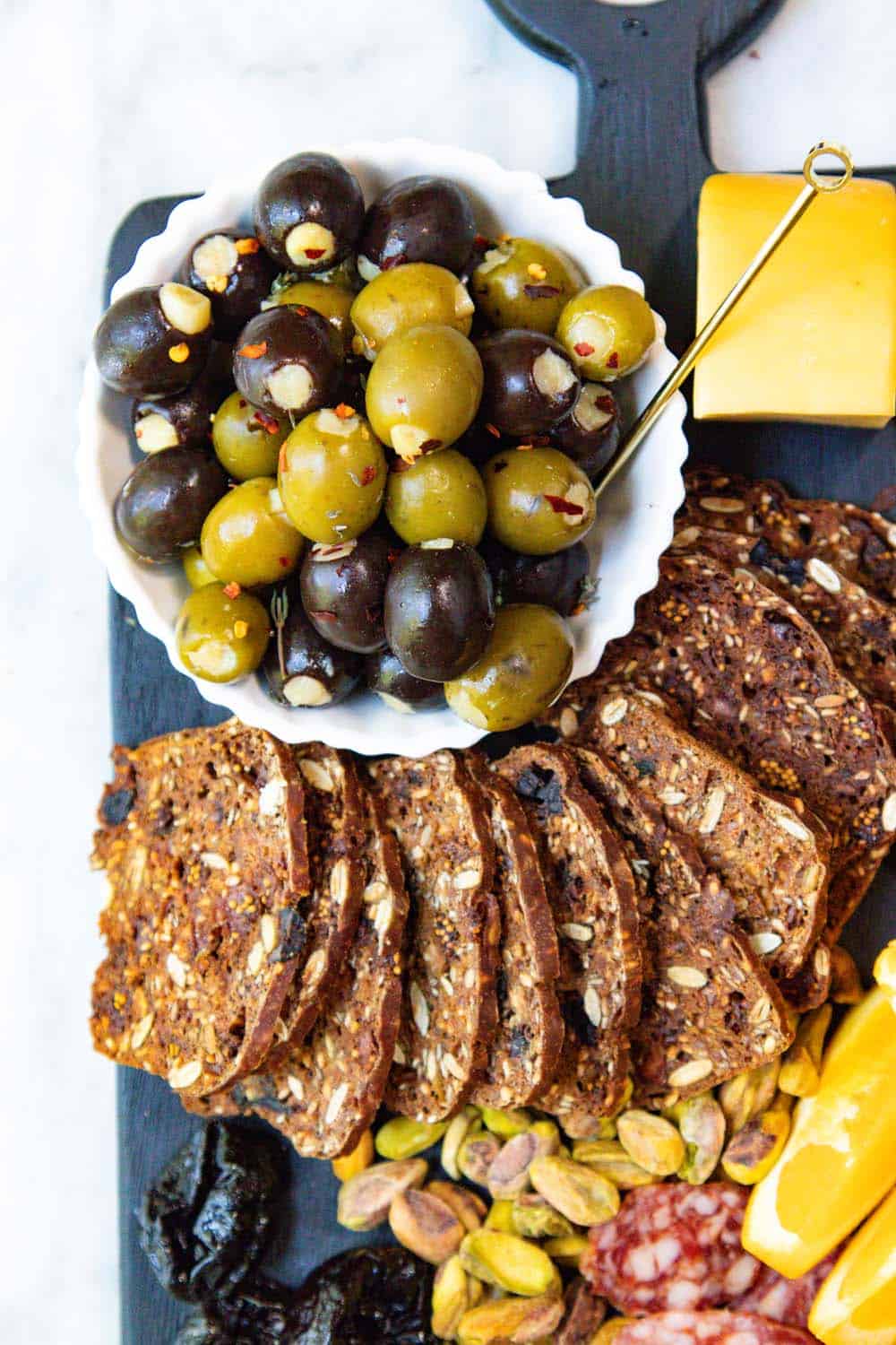 Stuffed olives and raisin crackers on a cheese board.
