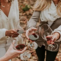 Women saying "cheers" with glasses of red wine in their hands.