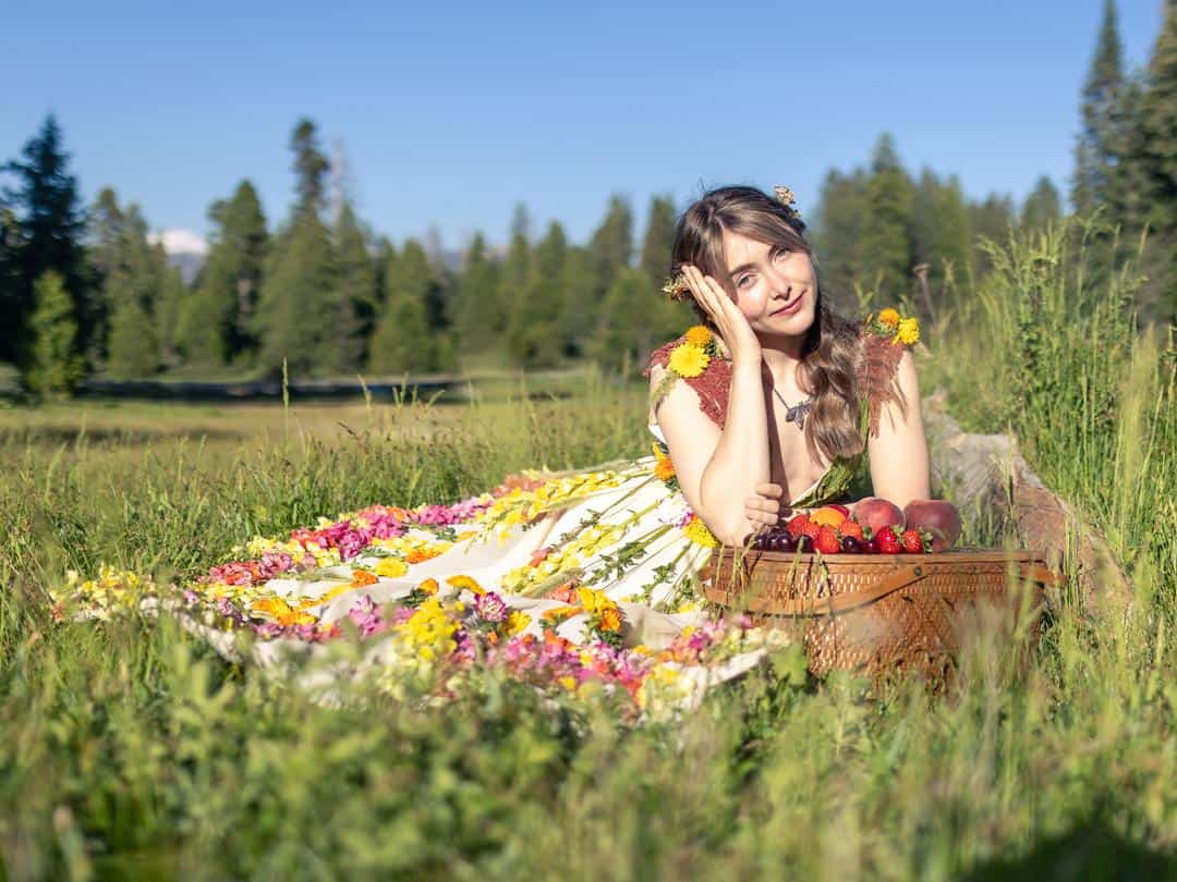 woman in a meadow leaning her head on a picnic basket