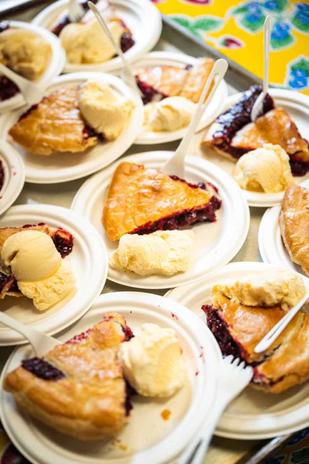 Slices of gizdich ranch pies on paper plates with a scoop of vanilla ice cream