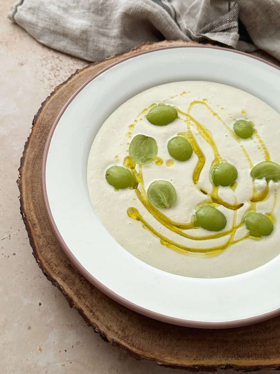 ajo blanco summer soup garnished with green olives and olive oil
