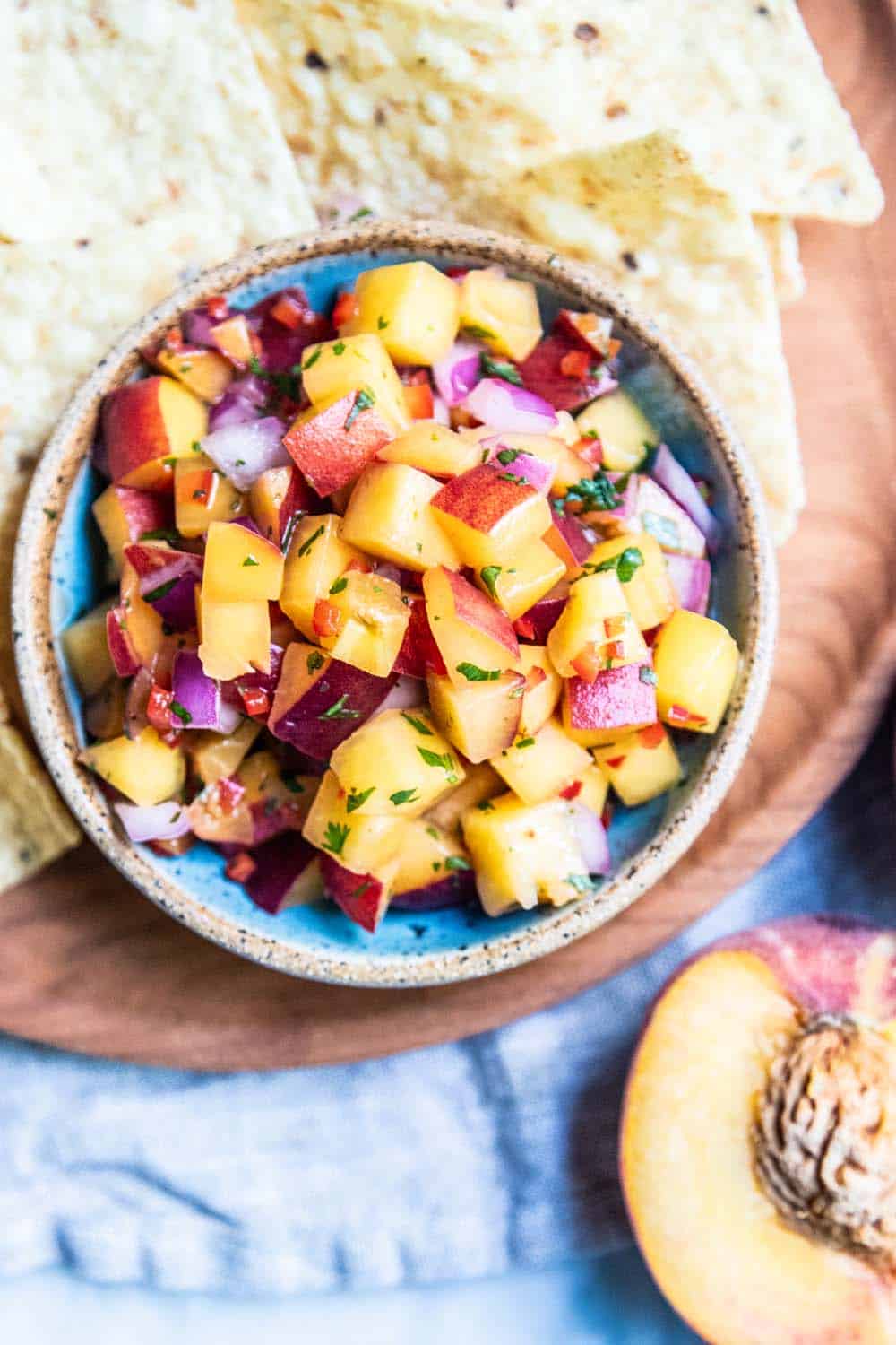 A bowl of peach salsa with tortilla chips.