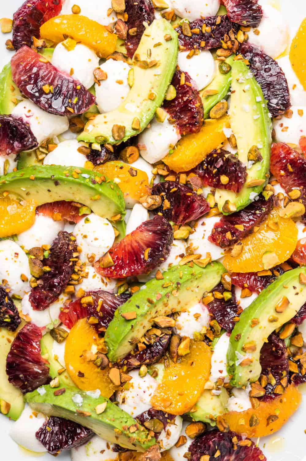 A caprese with avocado, three types of citrus. mozzarella, and pistachios.