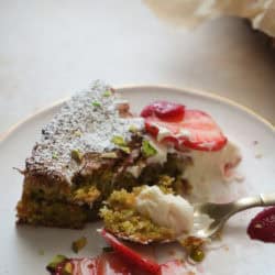 slice of pistachio cake with sliced macerated strawberries