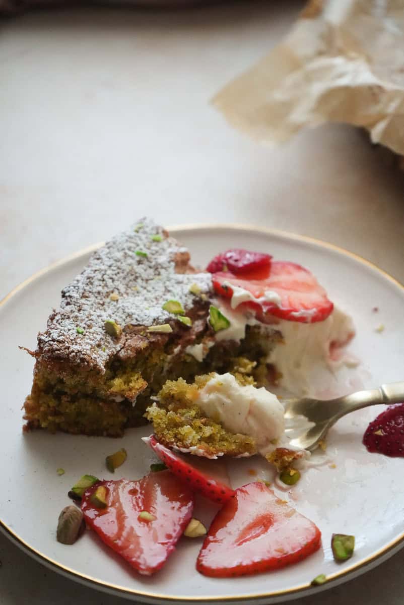 pistachio cake on a fork with mascarpone and sliced strawberries