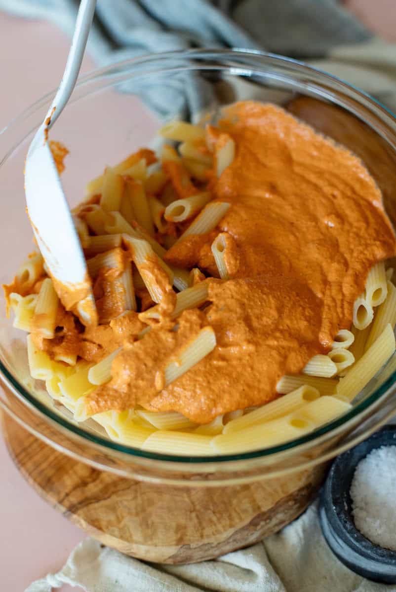 stirring into the red pepper sauce into pasta