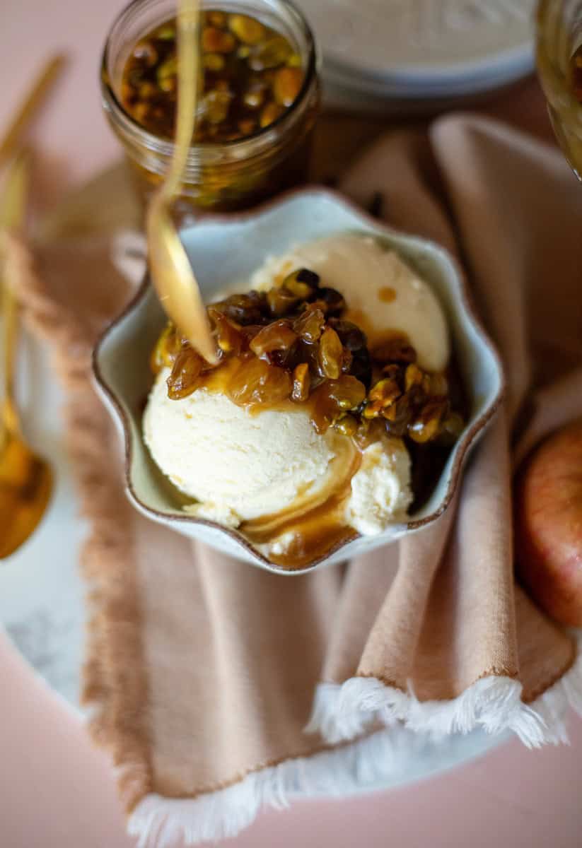 spooning honey caramel over vanilla ice cream