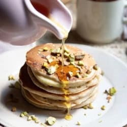 Pouring maple syrup over pancakes.