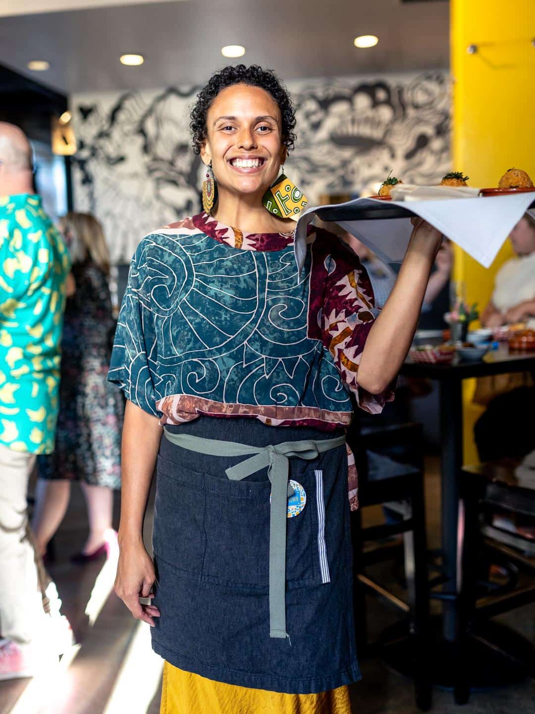 A member of the Magpie team smiles while passing around a tray of appetizers