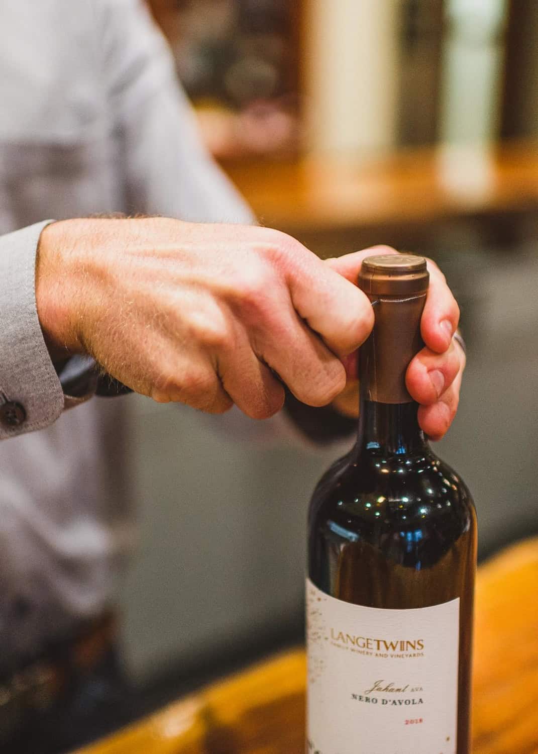 man (Joe Lange) opening a bottle of wine at the Lange twins tasting room
red wine: Nero d'Avola Redtail Vineyard . Jahant AVA