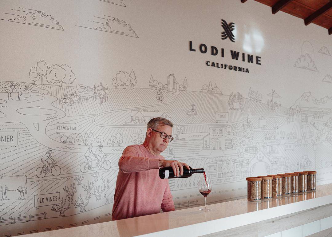 stuart, executive director of Lodi Wine and Visitor Center pouring a glass of wine