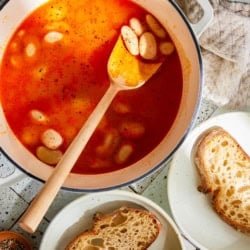 beans in tomato miso broth in a saucepan with slices of bread