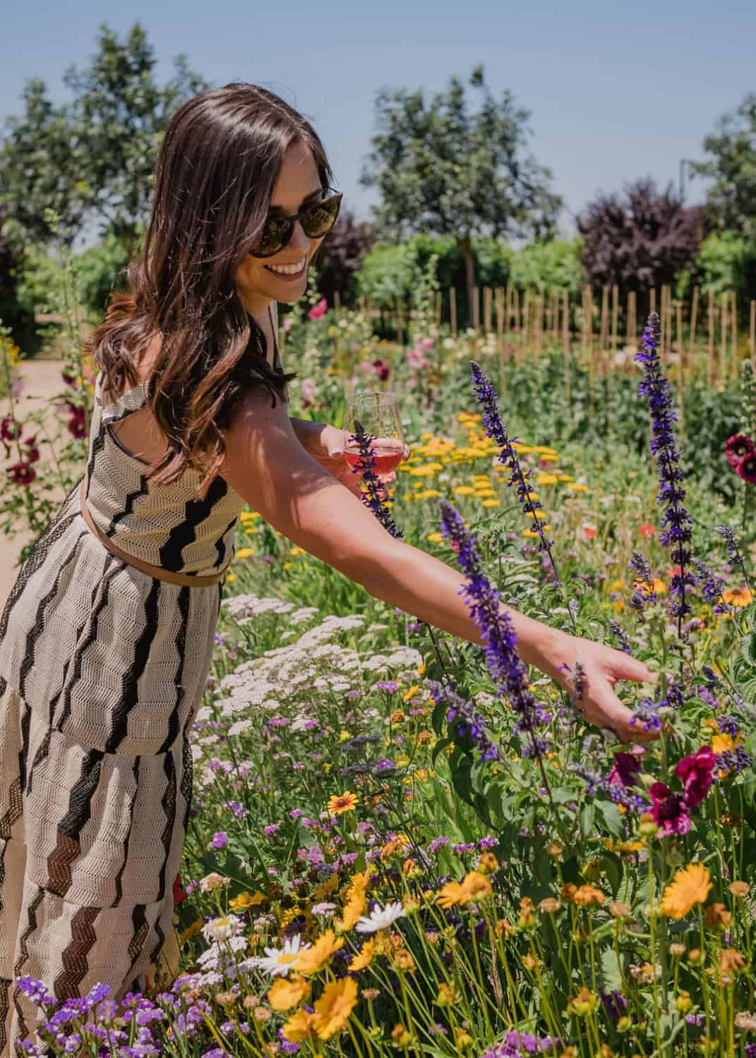 woman admiring the pollinator garden at Michael David with a glass of wine in hand