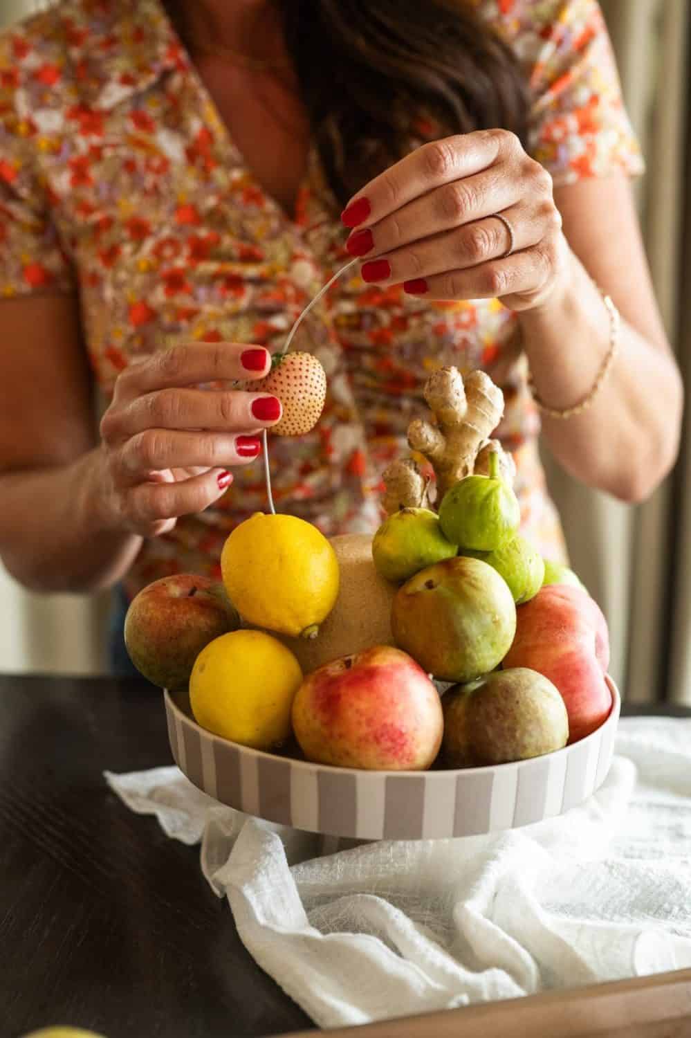 woman arranging fruit on a cake stand