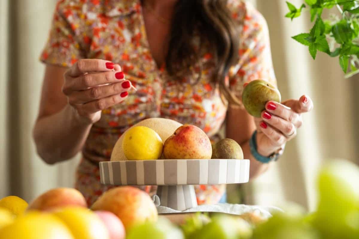 woman arranging fruit on a cake stand