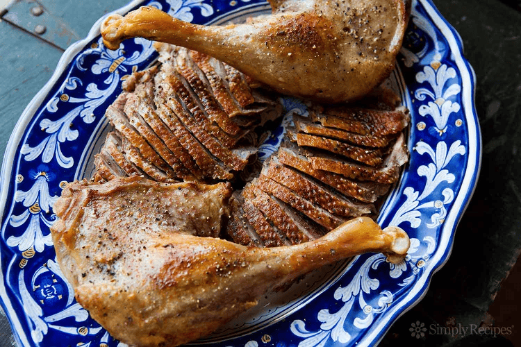 sliced roasted goose on a blue and white platter