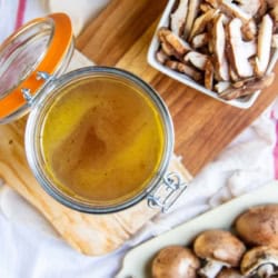 Two baskets of mushrooms next to a jar of mushroom broth.