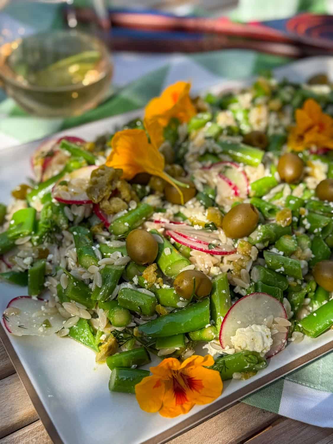 Alison Needhams spring orzo salad with smashed olive dressing garnished with nasturtium flowers