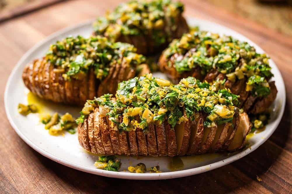 Hasselback potatoes with herbs and olives ready to serve.