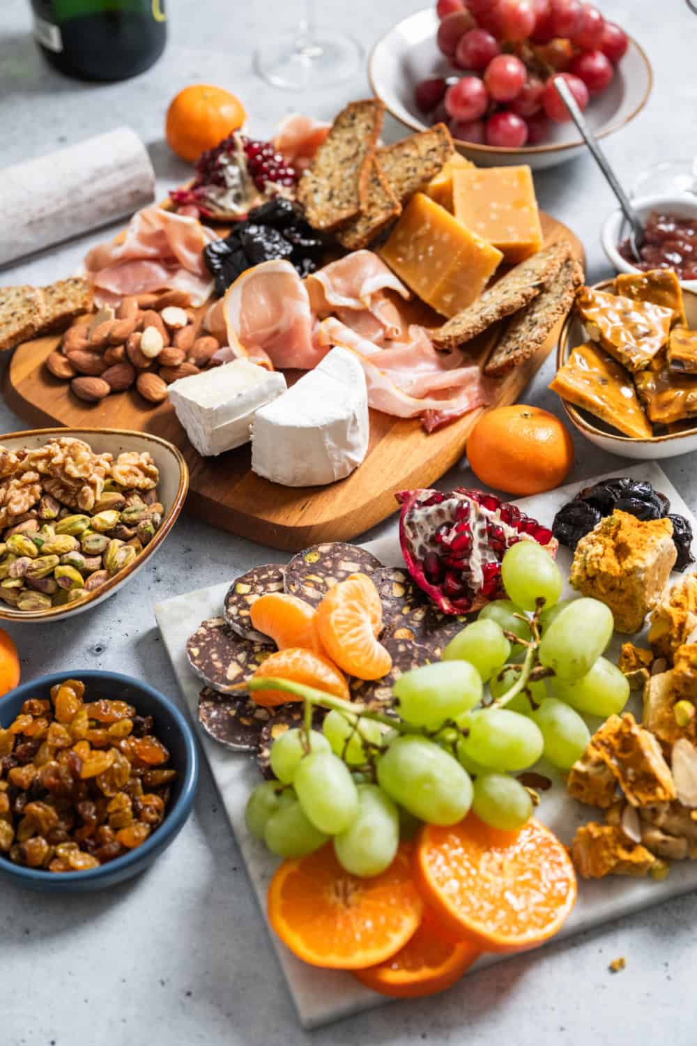dessert charcuterie board with Pistachio Nut Brittle, Honeycomb Candy, Mandarin & Fig Jam, table grapes, pomegranates, pistachio, almond, honey, prunes, raisins