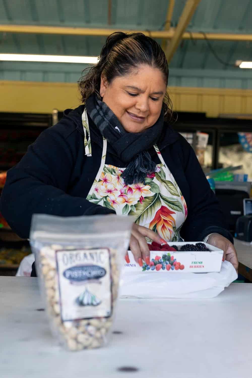 Woman putting a box of berries in a bag at Hayashi Fruit Stand