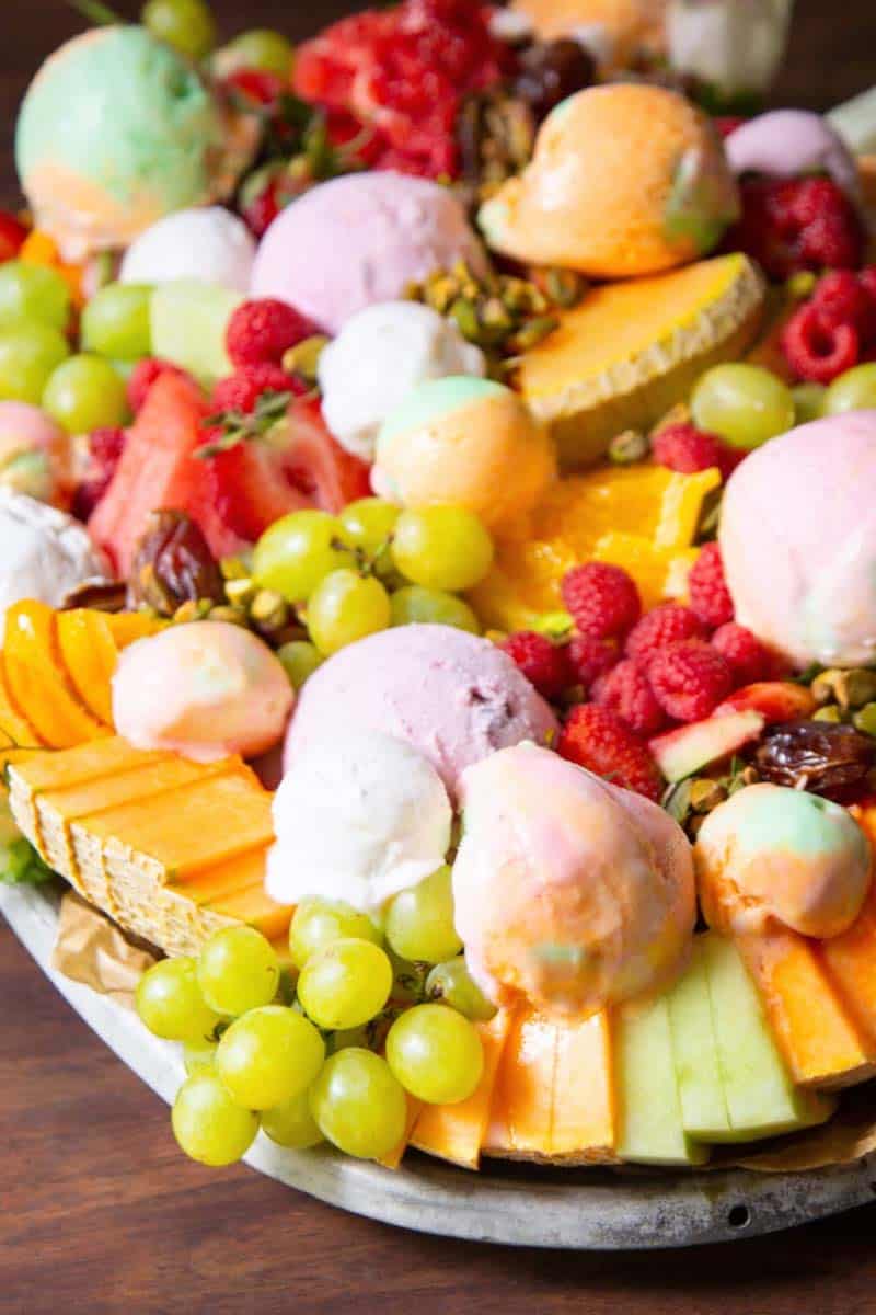 Melon slices, grape clusters, raspberries, dates, pistachios, and ice cream scoops.
