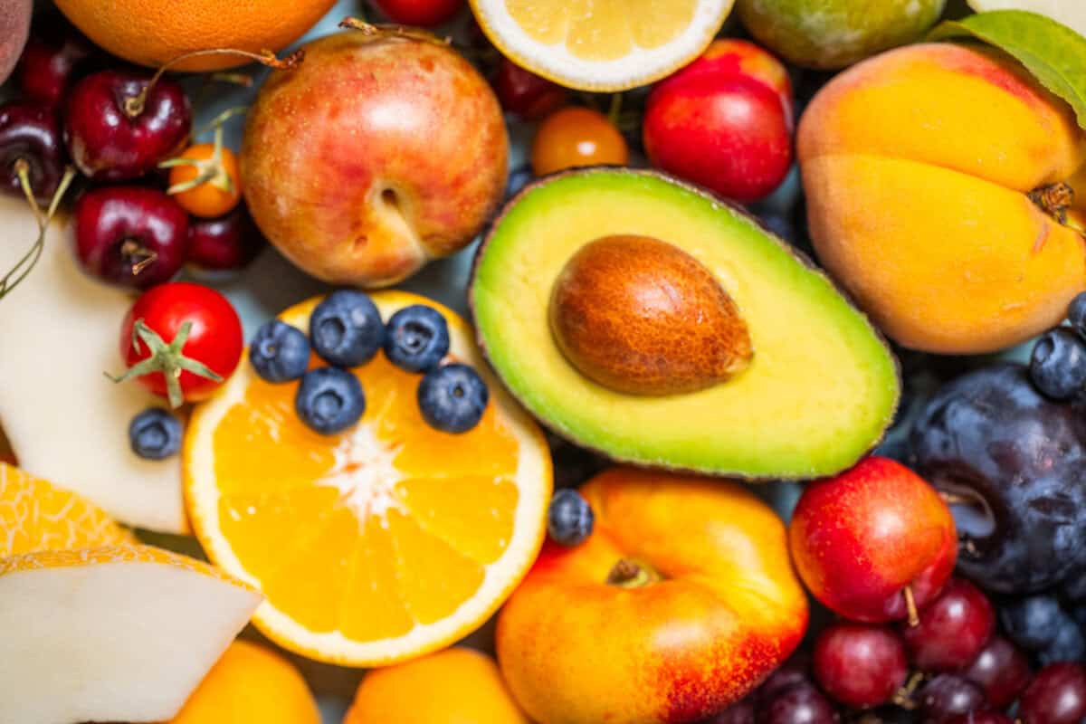 flat lay of avocado, citrus, stone fruit and berries