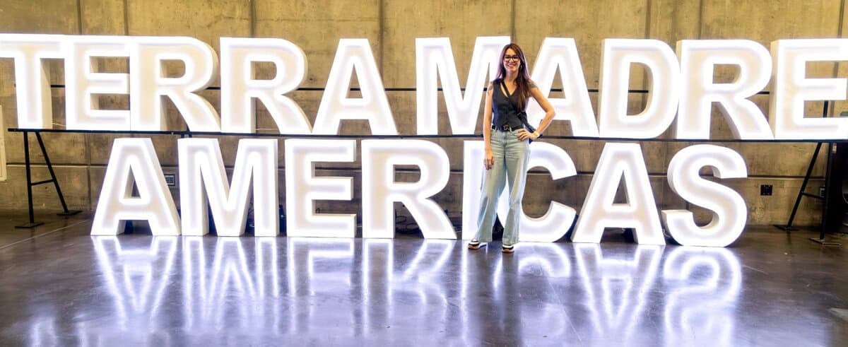 Meg van der Kruik standing in front of the Terra Madre Americas sign 