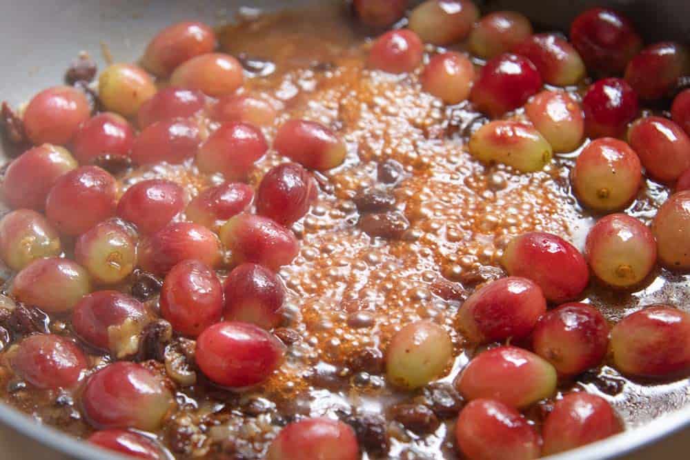 Red table grapes simmering in chicken pan drippings, wine, and win soaked raisins.